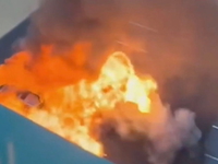 A silver vehicle exploding into a fireball in a parking lot