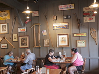 Cracker Barrel customers eat next to an interior wall with antiquities on it.
