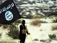 Islamic State militant holds ISIS flag in a desert setting