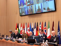 NATO Chiefs of Defense sit at a conference table with flags behind them during a virtual meeting on Ukraine
